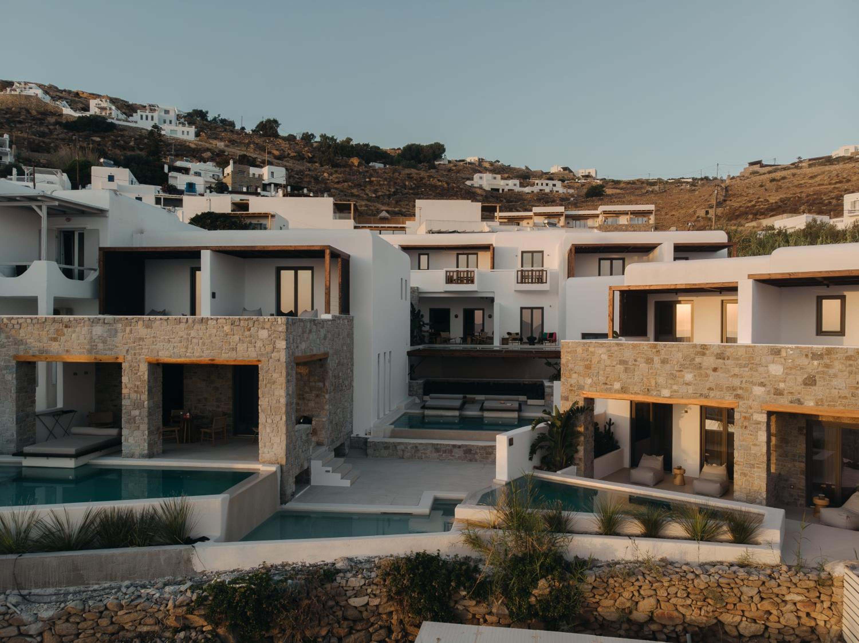 The hotel at dusk: stone and whitewashed buildings with private pools set into the hillside