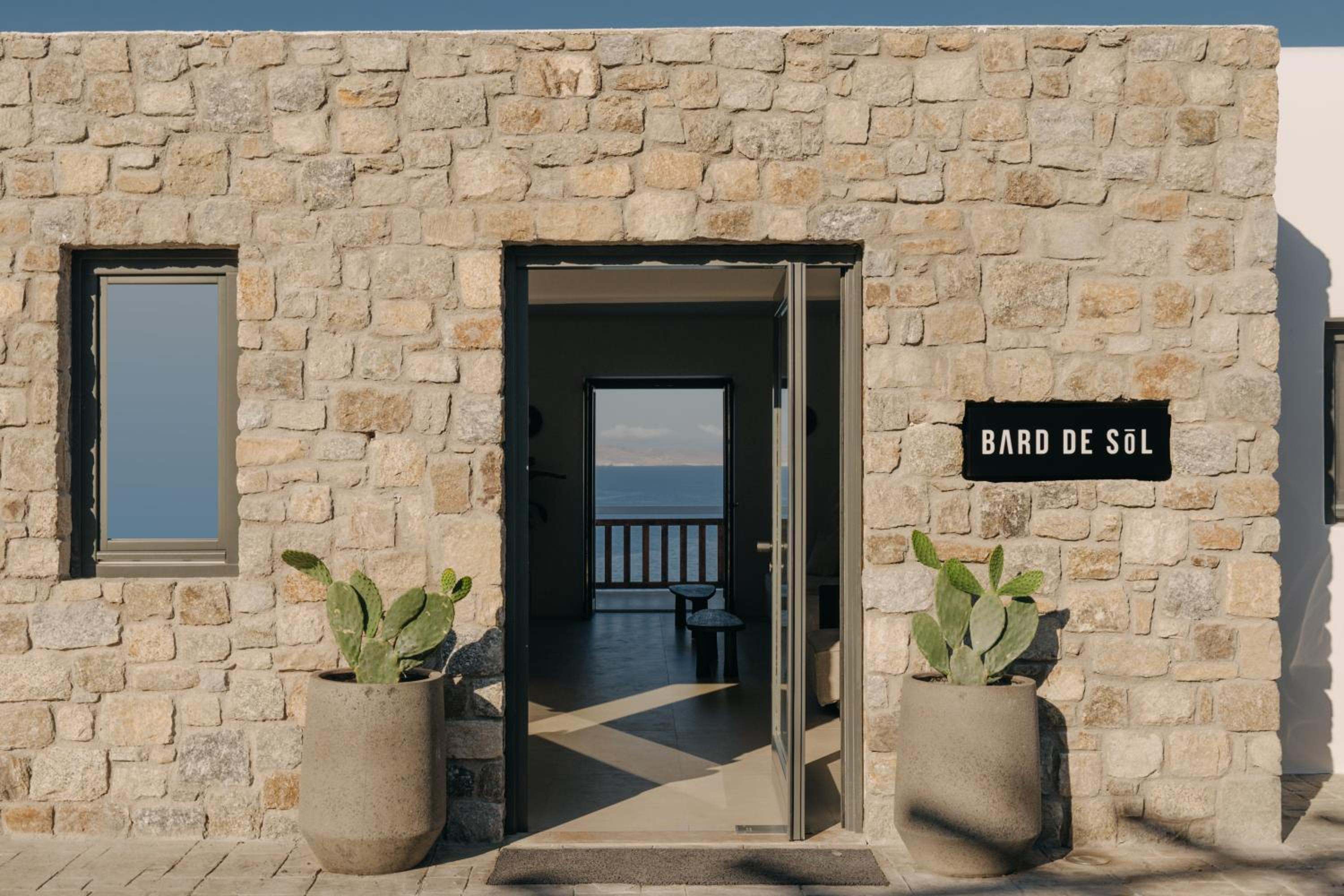 The stone entrance with the Bard de Sōl sign, flanked by potted cacti