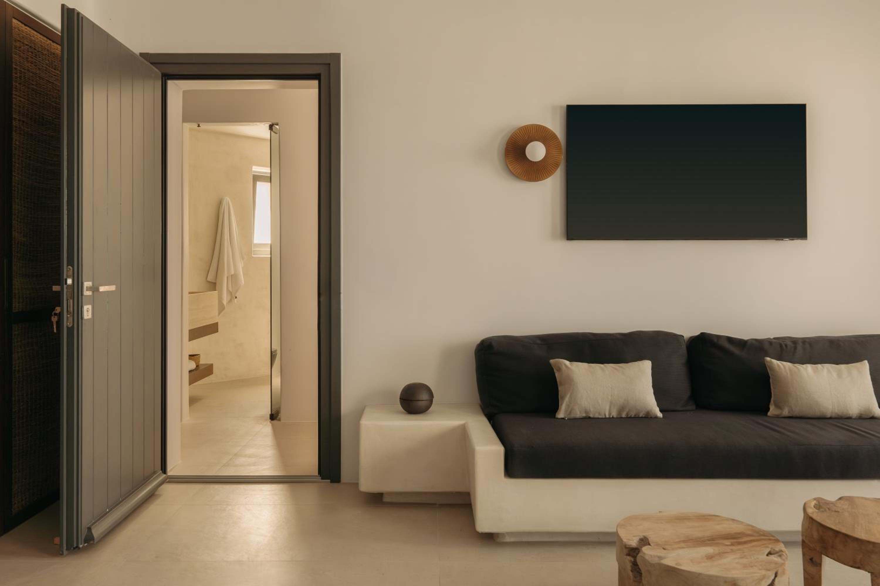 A lounge with built-in seating, a dark sofa and a wall-mounted screen