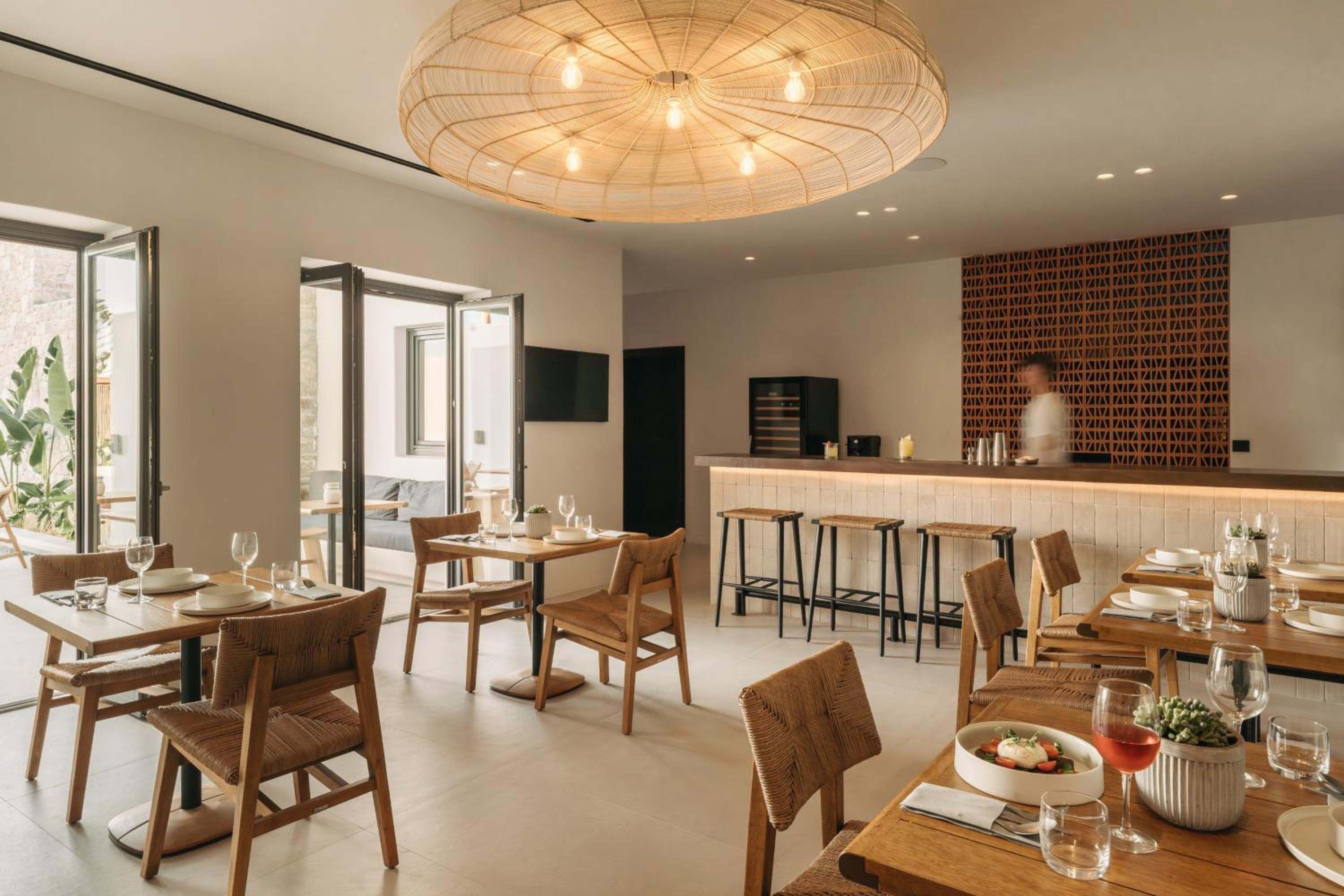 The restaurant interior: timber tables, a woven pendant light and the bar beyond