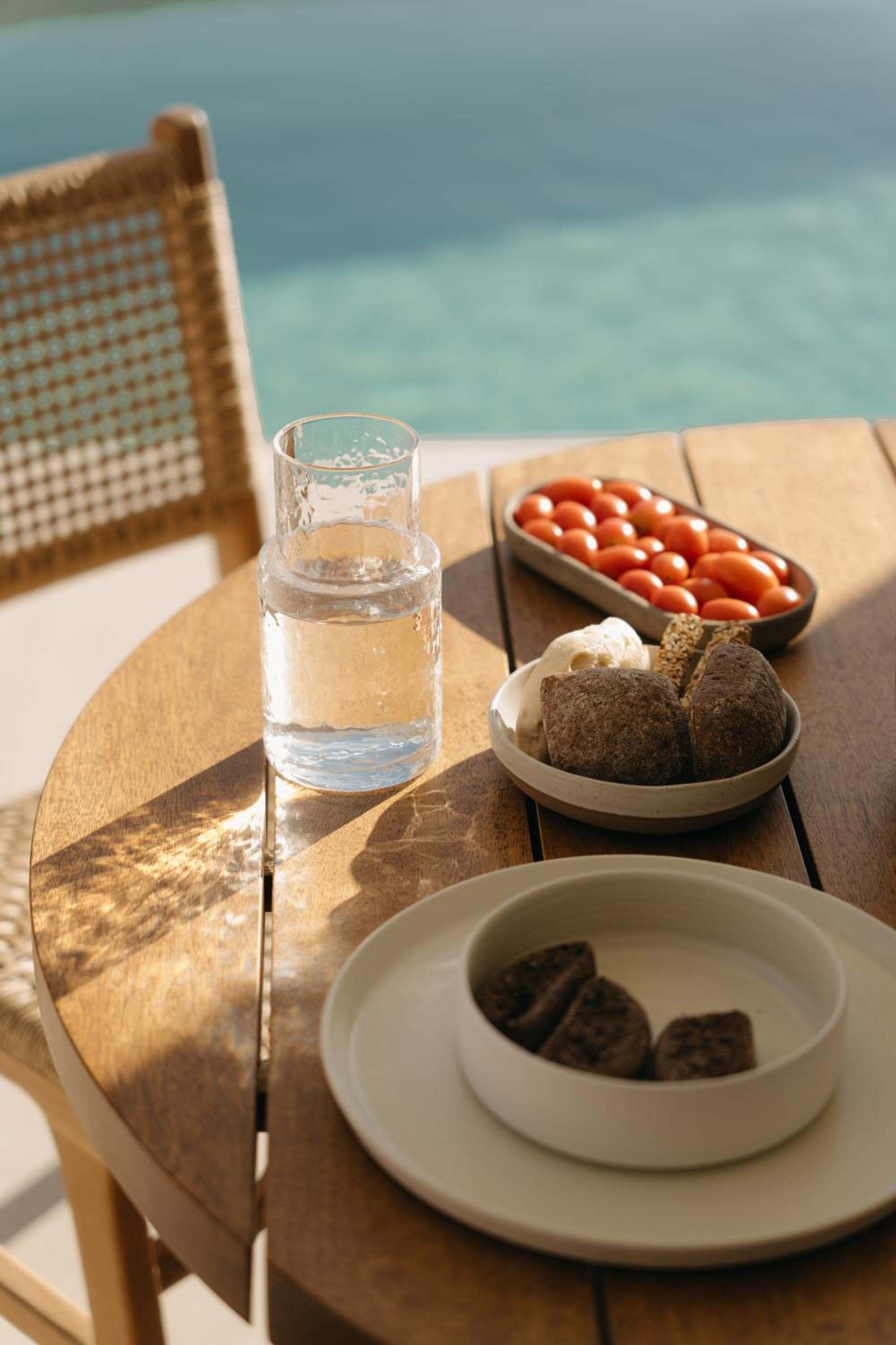 Bread, tomatoes and water on a round table by the pool