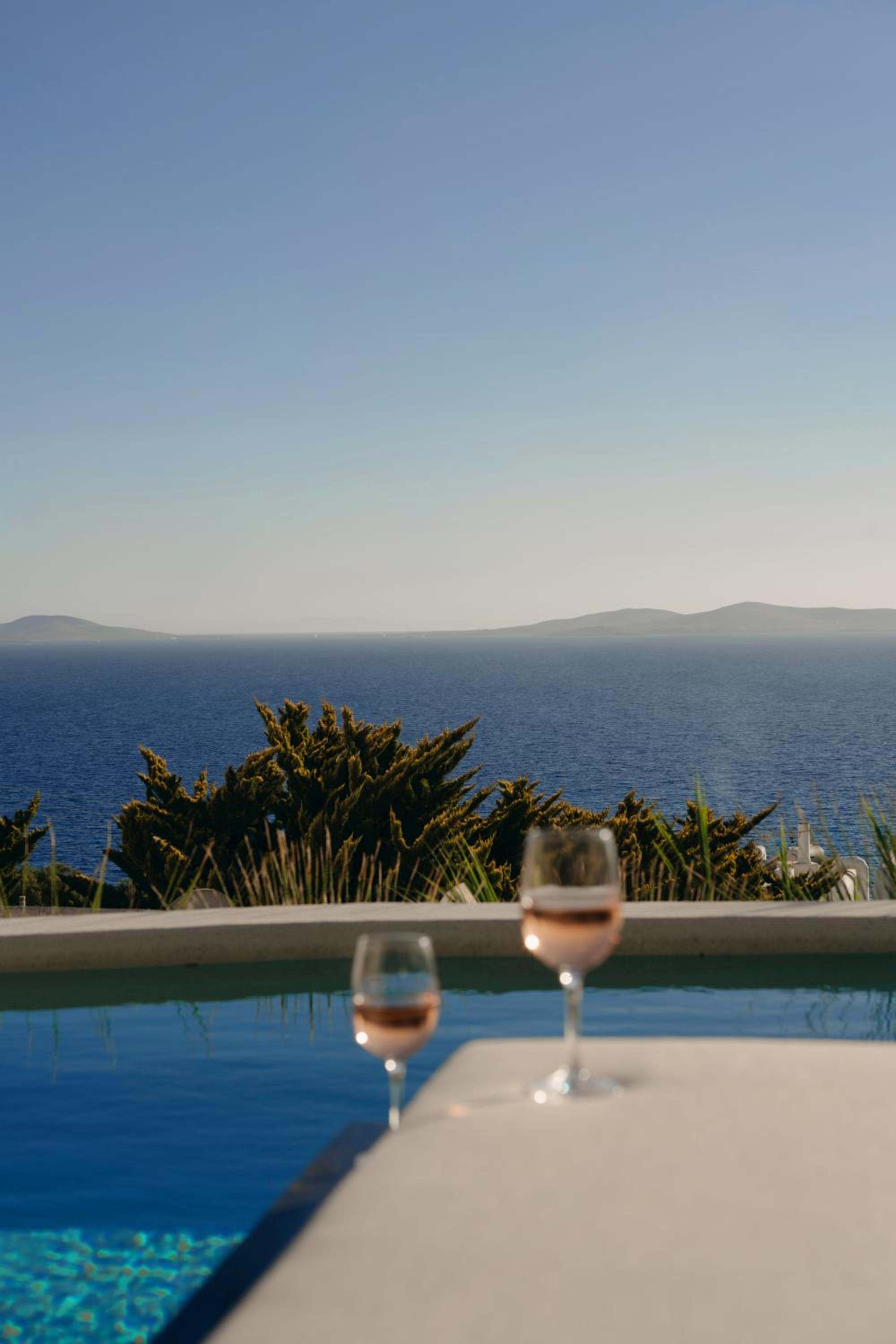 Two glasses of rosé on the edge of a pool, the sea and islands beyond