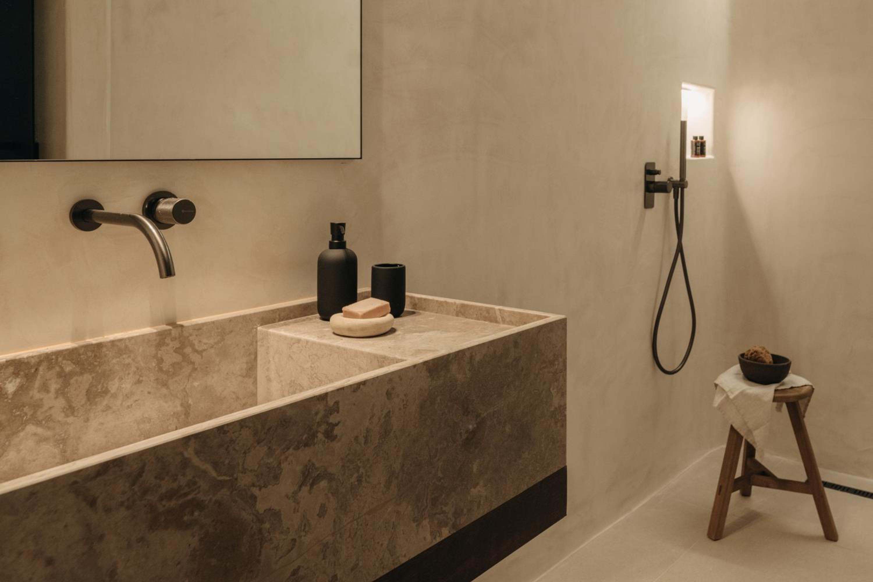 A carved stone basin with dark brassware