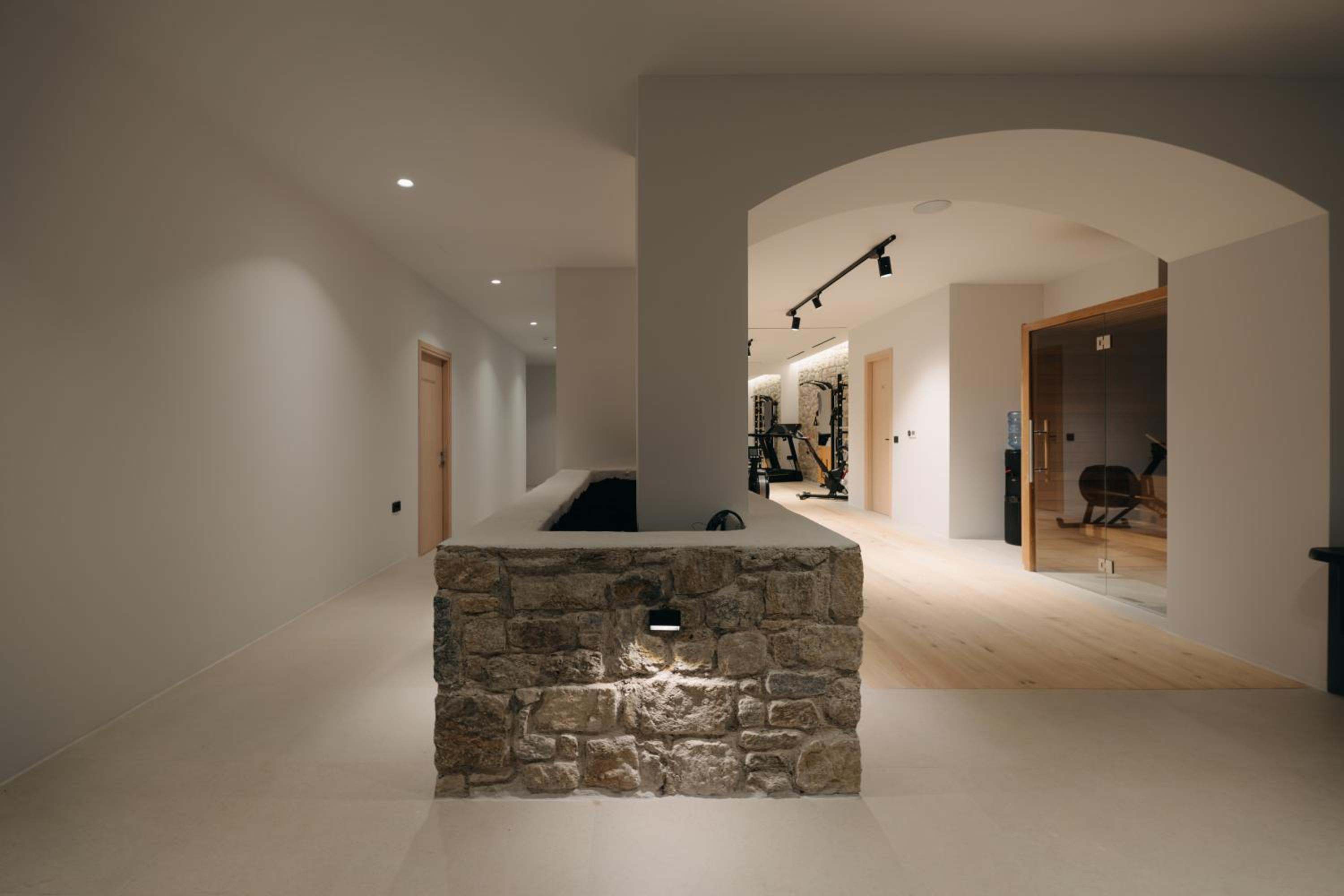 An arched corridor with a stone planter, leading towards the gym