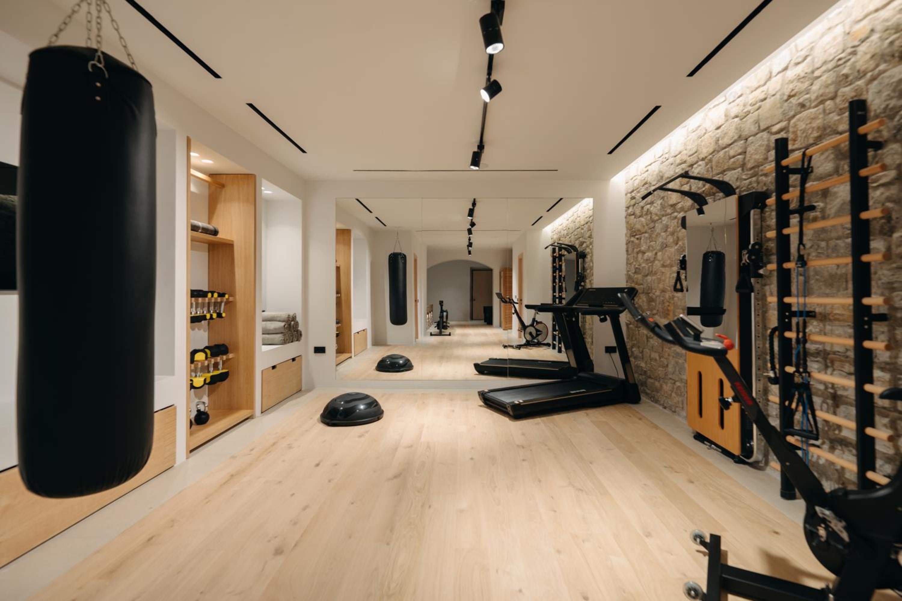 The gym, with a treadmill, wall bars, a punchbag and a timber floor