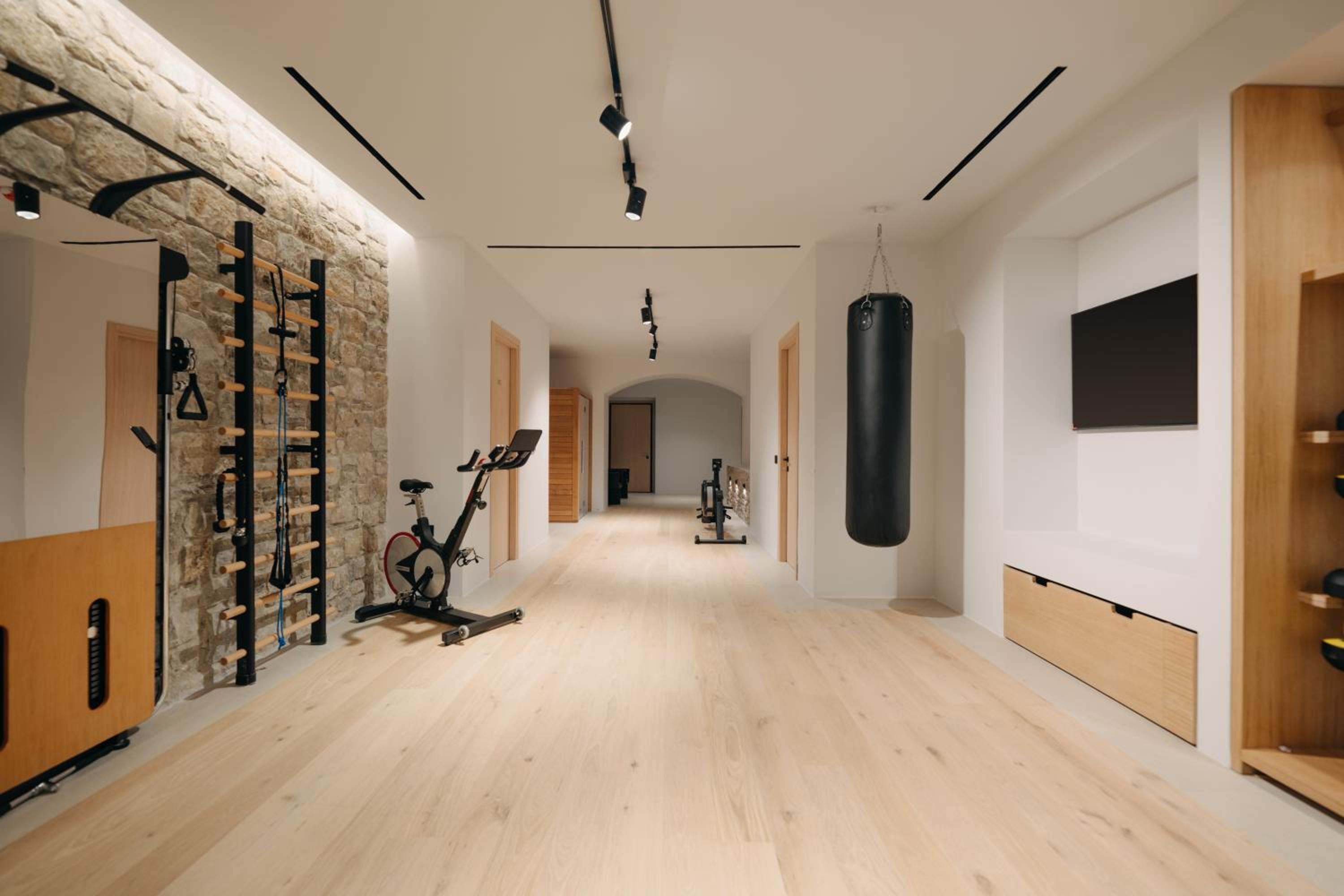 The gym, with an exercise bike, wall bars and a punchbag beneath a stone wall