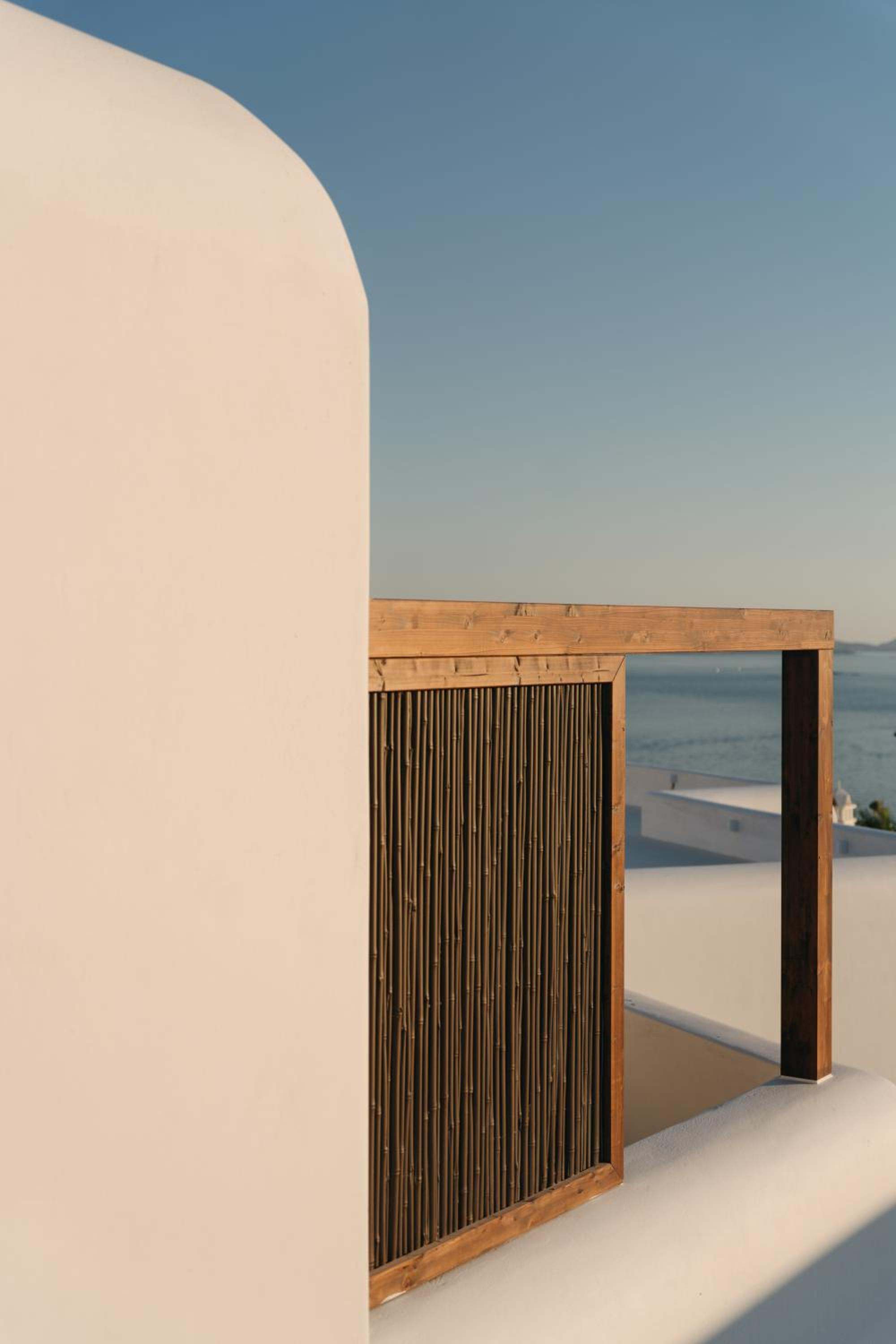 A whitewashed wall and a slatted timber screen against the sky