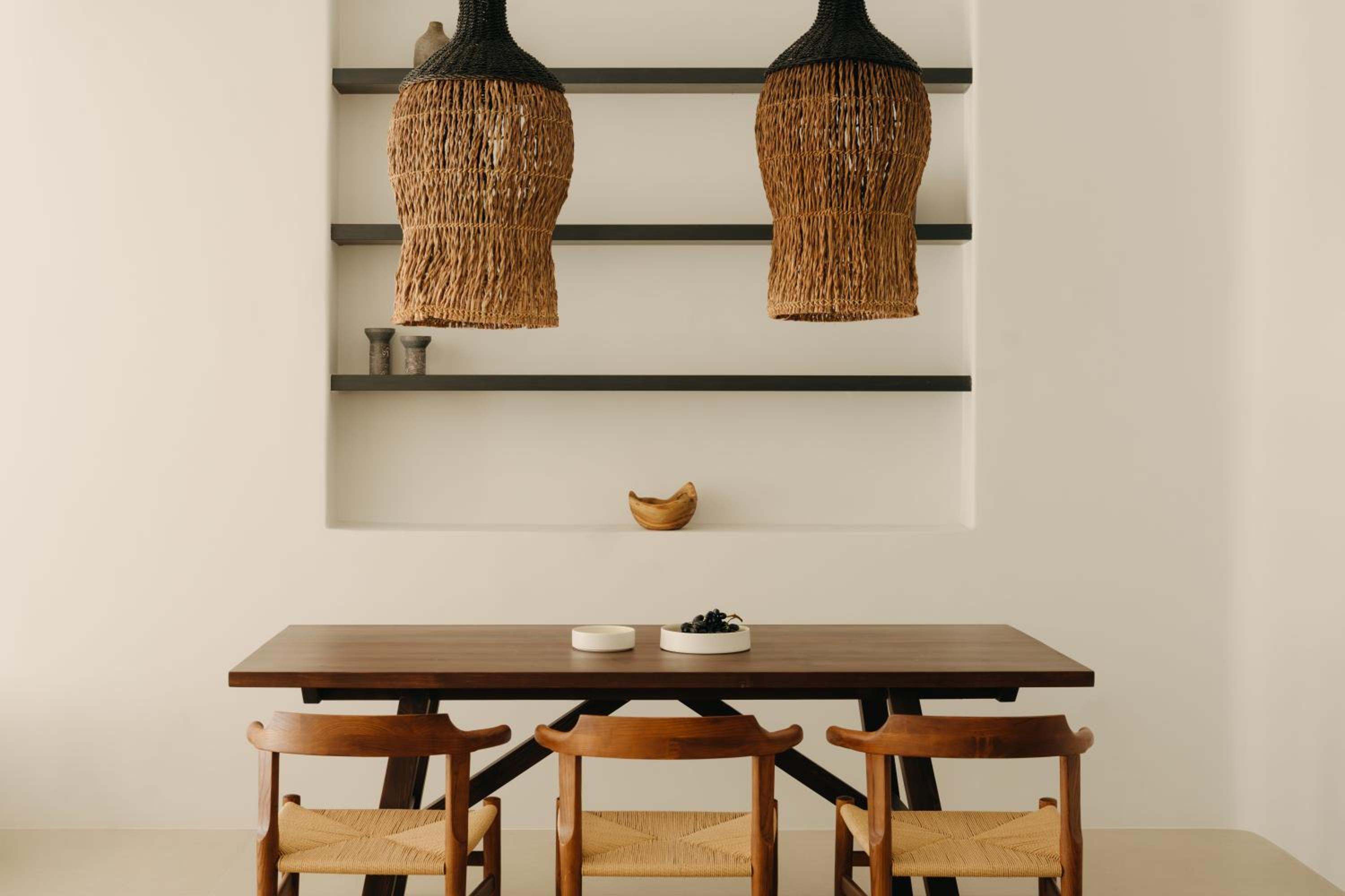 Del Sol Suite: a timber dining table beneath woven pendant lights