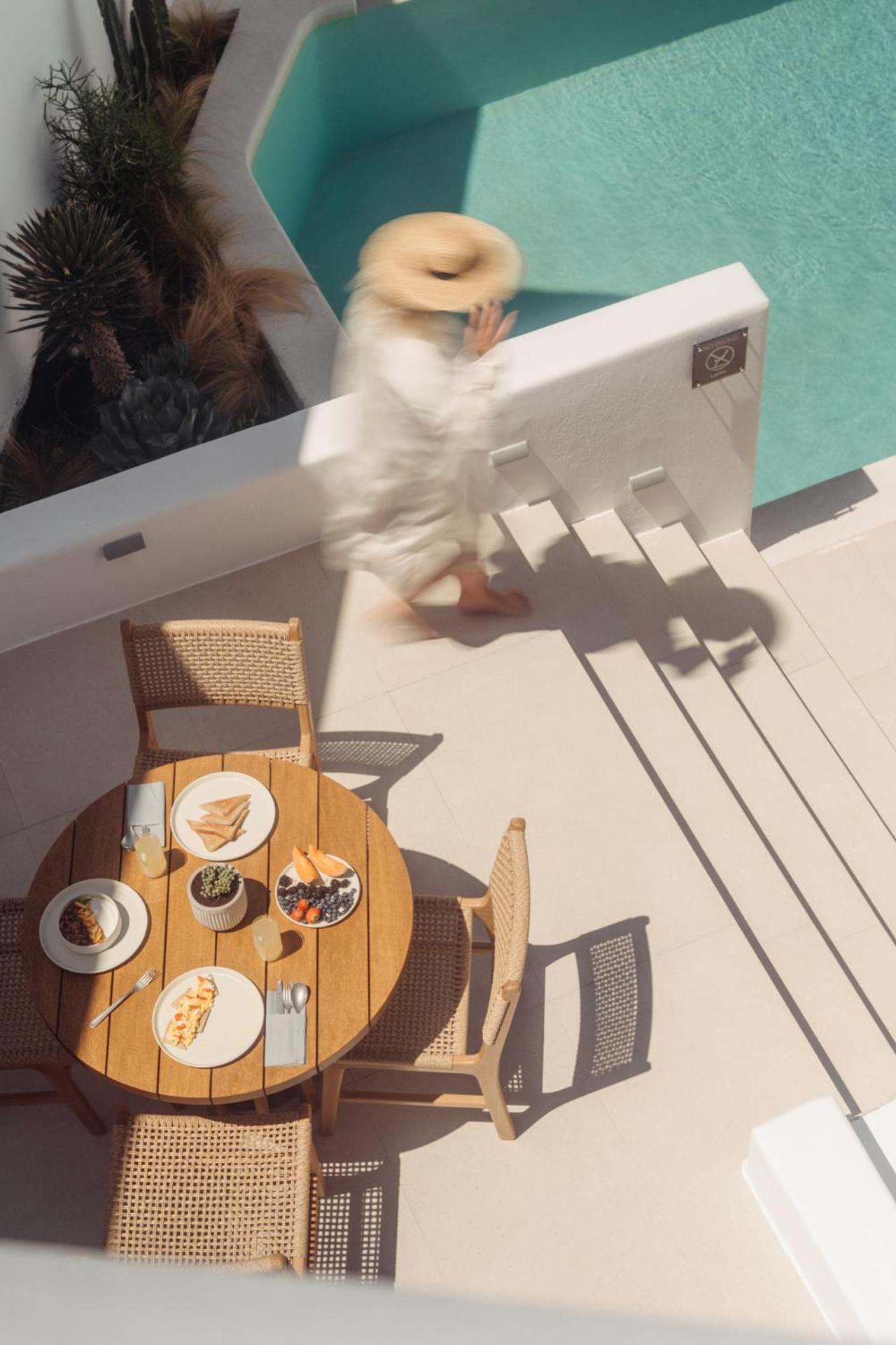 Del Sol Suite: seen from above, a guest walks down steps past a breakfast table by the pool