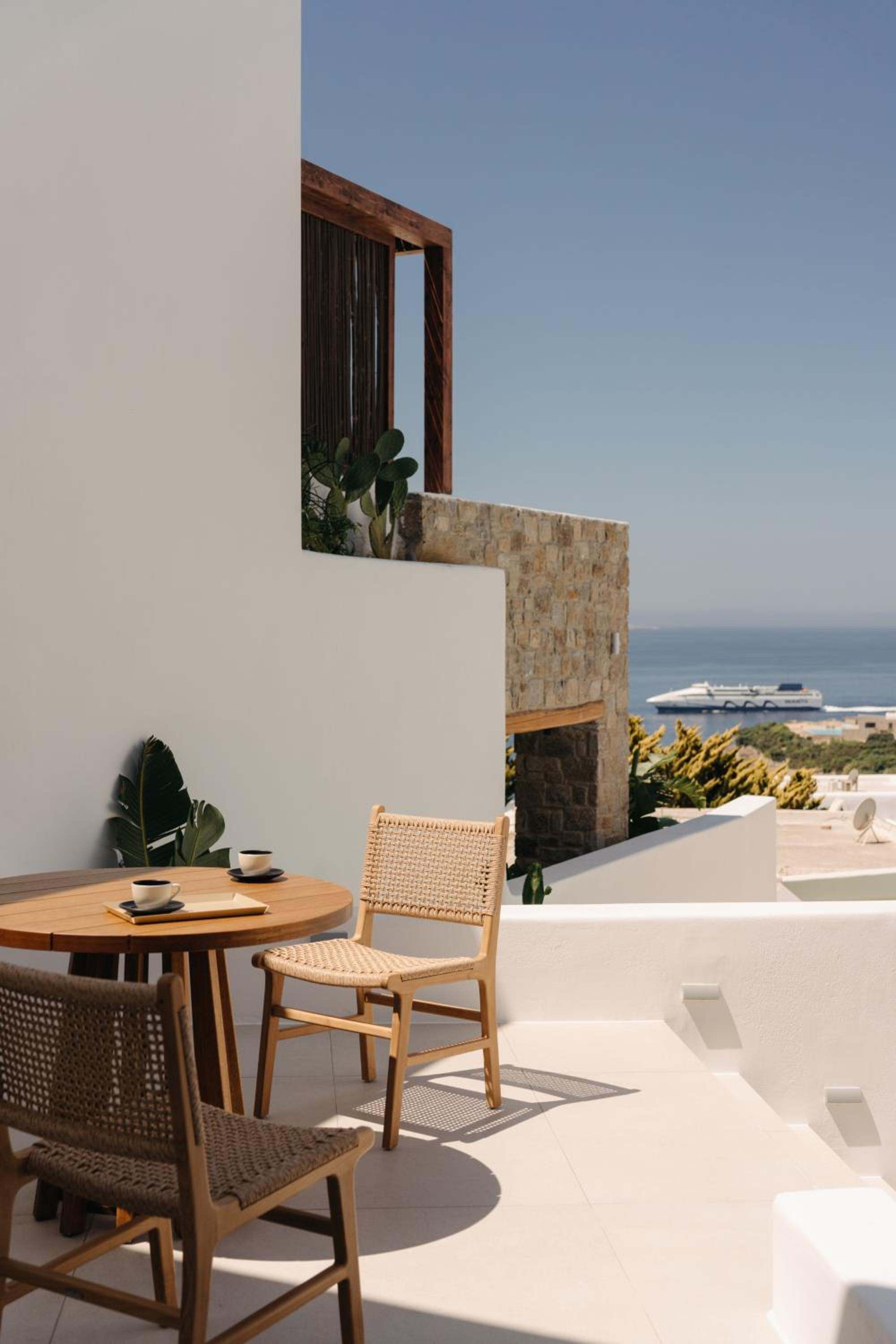 Del Sol Suite: a small table and two chairs on a terrace, with the sea in the distance