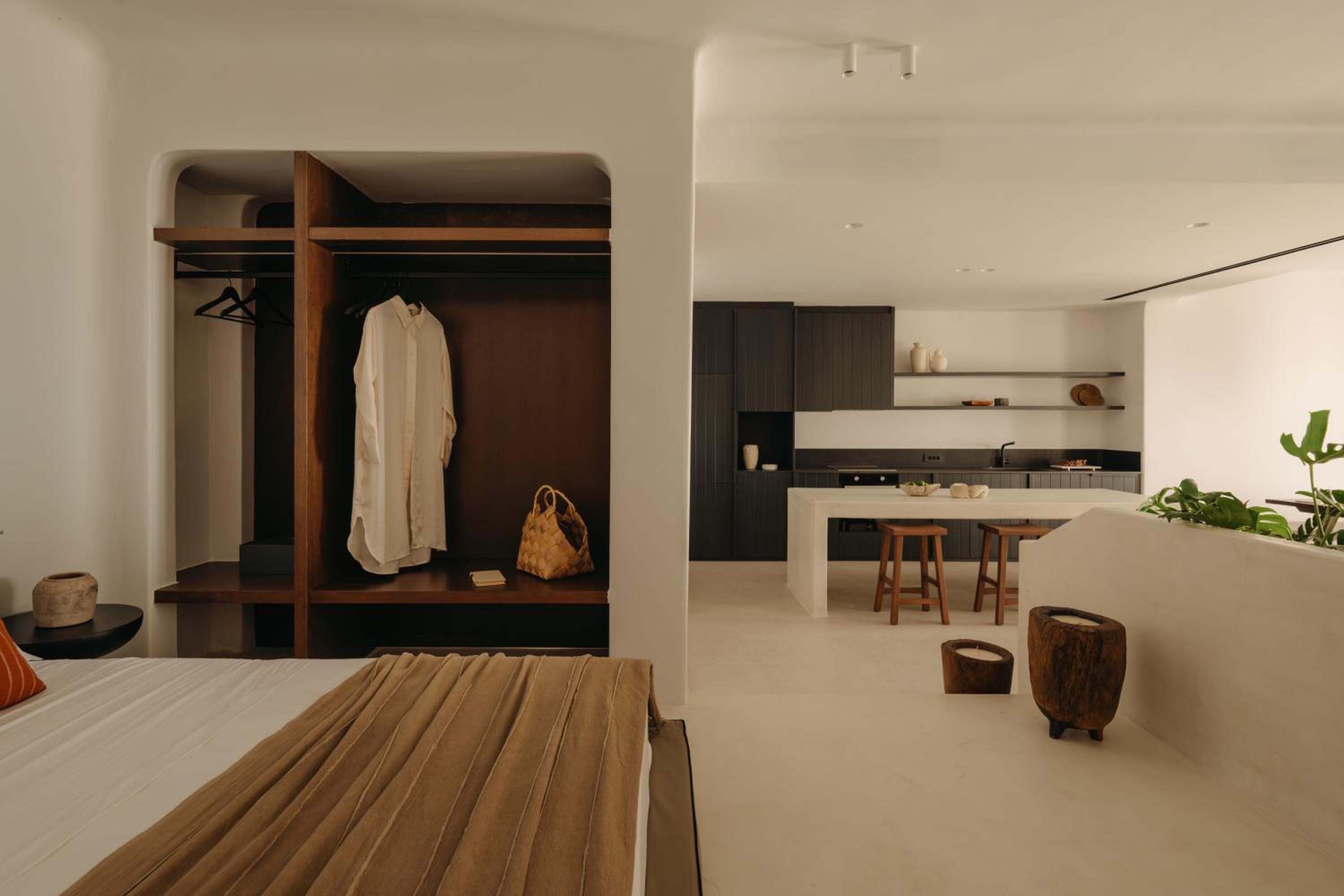 Premier Suite: an open wardrobe beside the bed, with the kitchen beyond