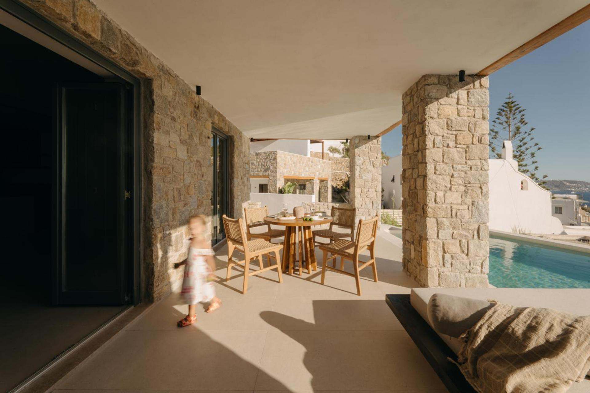 Premier Suite: a covered stone terrace with a dining table beside the pool