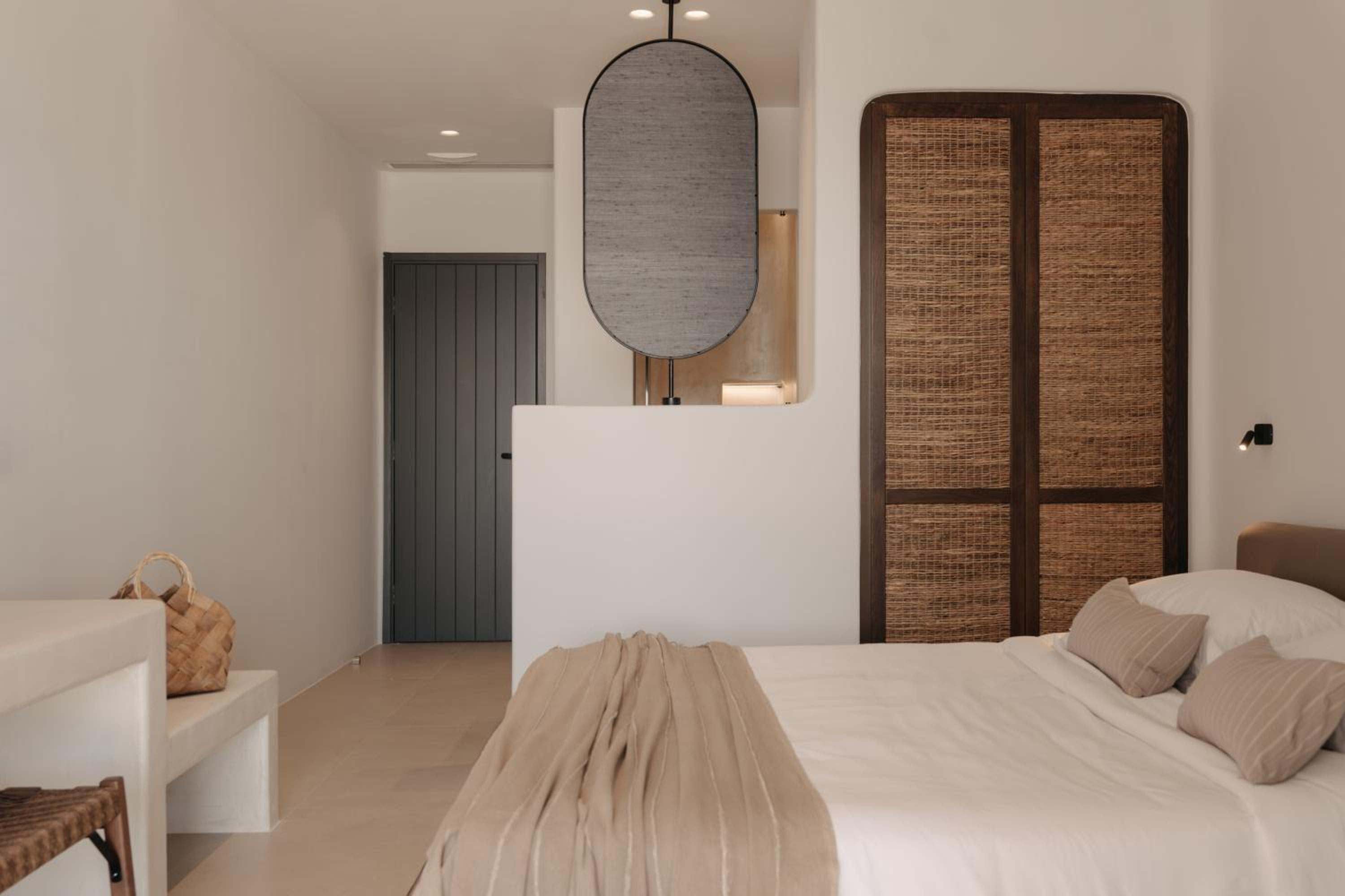 Junior Suite with Outdoor Hot Tub: the bed, a woven wardrobe and an oval mirror