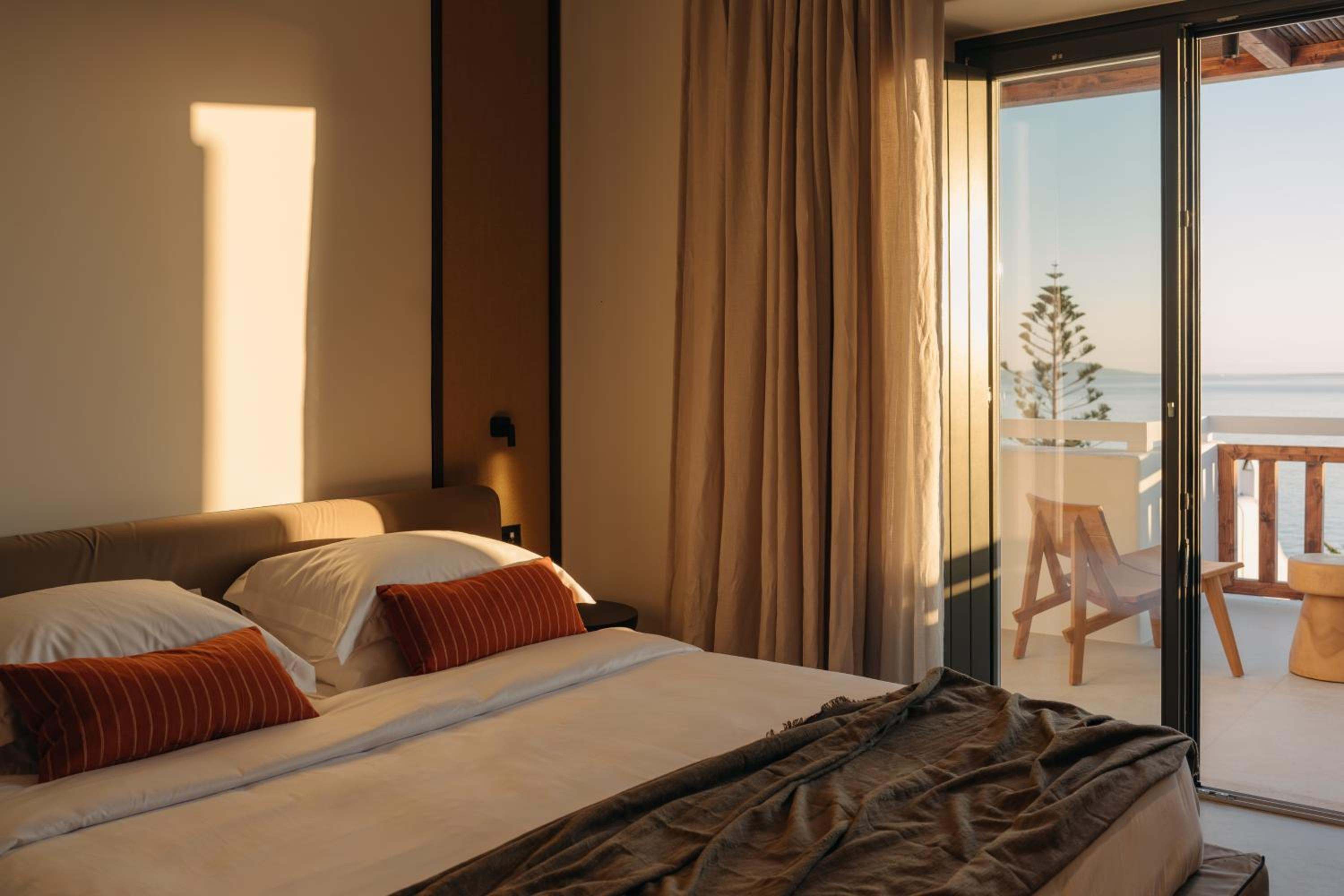 Junior Suite with Outdoor Hot Tub: evening light across the bed, with the balcony beyond