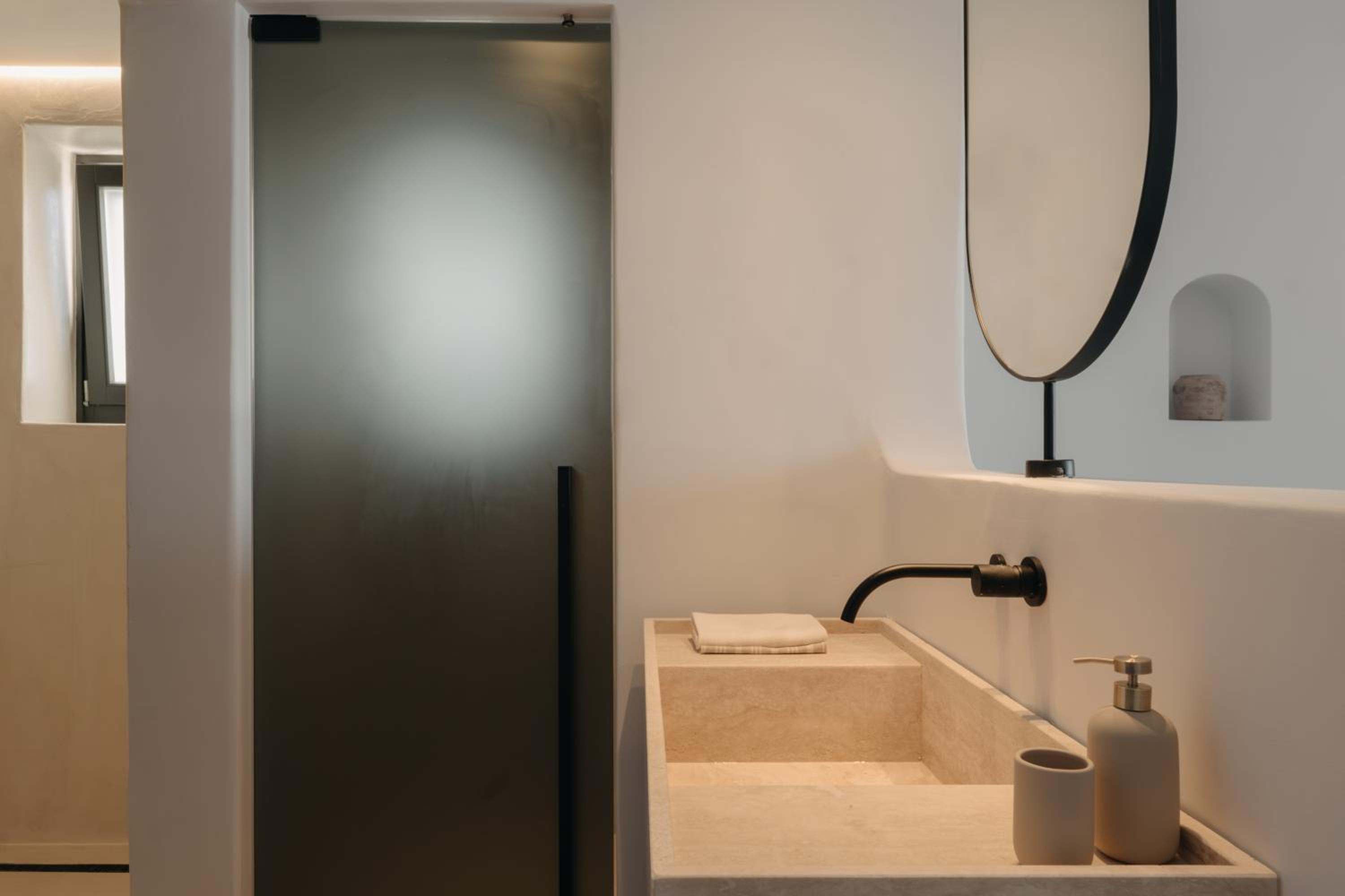 Junior Suite with Private Pool: a stone basin, an oval mirror and a glass shower door