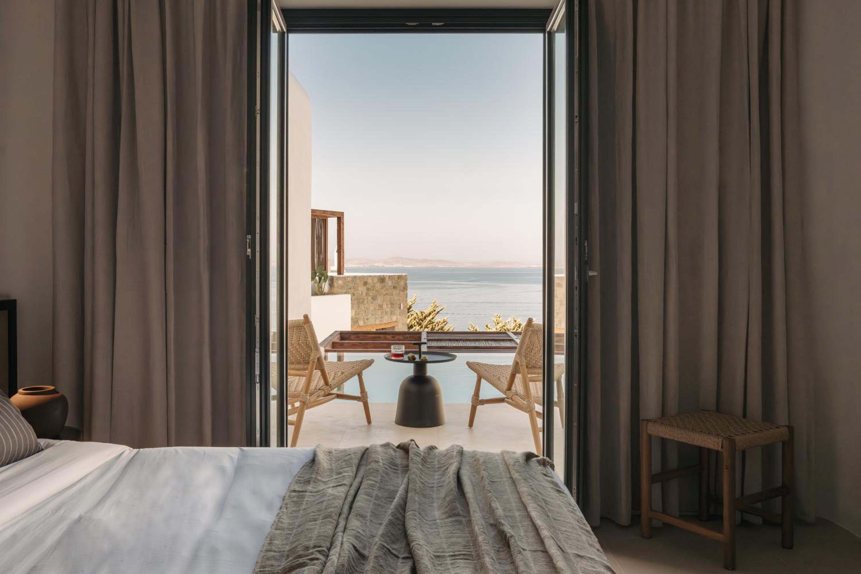 Superior Room: the bed, with doors open to a terrace, the pool and the sea